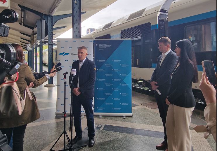 Fotografija iz novinarske konference, predstavniki SŽ in Direkcije za infrastrukturo na peronu, v ozadju vlak Stadler Flirt.