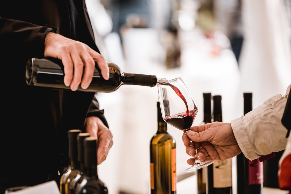 Oseba nataka vino v kozarec.